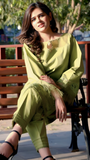 Woman in a green traditional outfit sitting on a bench outdoors