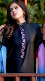 Woman wearing a black blouse with floral embellishments in an outdoor setting